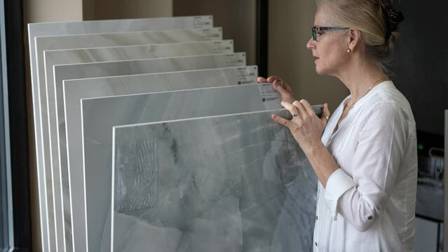 Happy mature woman looking at samples marble stone in a store for a home renovation redecorating project.