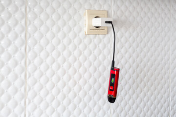 The new system electronic cigarette is charged at a 220V outlet with a charger, general view. Vape...