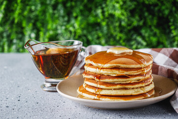 fresh tasty pancakes with maple syrup on a light stone background