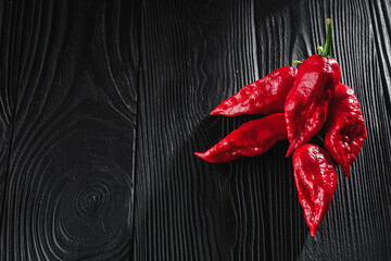 fresh red extra hot bhut jholokiya pepper on black wooden rustic background