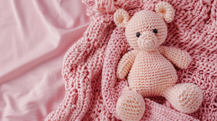 Fototapeta premium A cozy pink crocheted teddy bear nestled in soft knitted fabric.