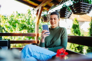 One young caucasian woman is using her smartphone to talk with friends or send messages while...