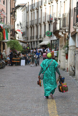 woman walking selling lucky necklaces and charms to passersby in a historic European city center...