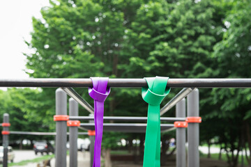 Purple and green Elastic rubber bands for exercise tied on a horizontal bar
