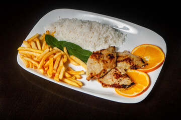 Gourmet grilled pork tenderloin served with rice and crispy fries, enticingly arranged on a white plate.