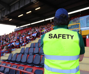 stadium steward with the phosphorescent jacket and the SAFETY writing who controls the fans in the packed stands © ChiccoDodiFC