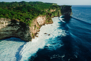 Rocky cliff coastline and ocean with waves near Uluwatu temple in Bali