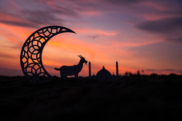 Eid Mubarak greeting background, Crescent moon shape with goat and mosque against sunset sky in the...