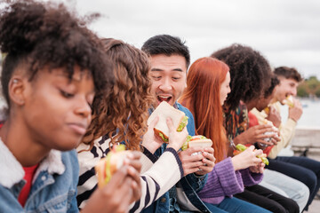 Group of young people from different cultures having a snack together outdoors. Concept: lifestyle