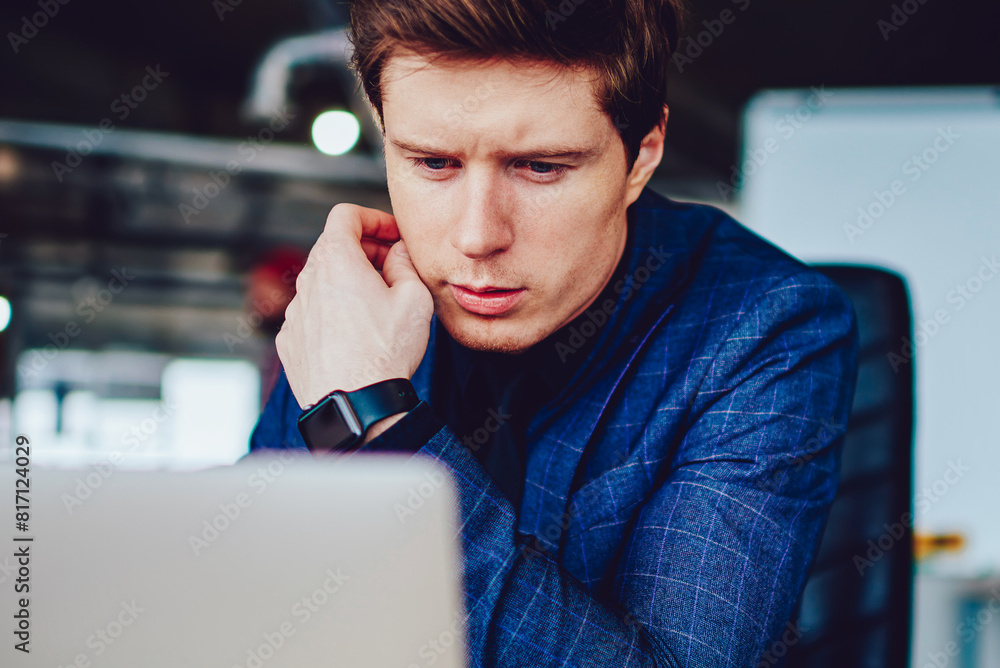 Poster puzzled caucasian male director of company searching information while browsing internet via modern 