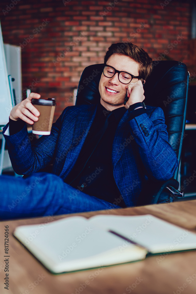 Poster successful businessman making positive conversation via app with friend while enjoying caffeine beve