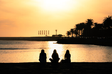 three silhouettes contemplating the sea at sunset