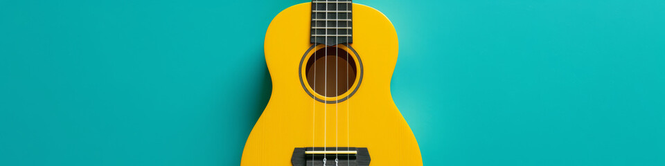 Obraz premium Bright Yellow Ukulele on a Teal Background for Musical Concept