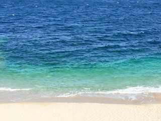 Blue and bright turquoise sea and sandy beach horizontal background.