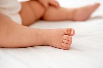 the legs of a small child on a white background on the bed, a pl
