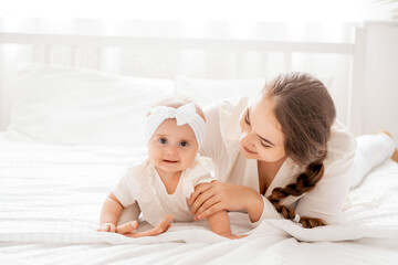 mom and baby are playing and rejoicing in a bright white room on