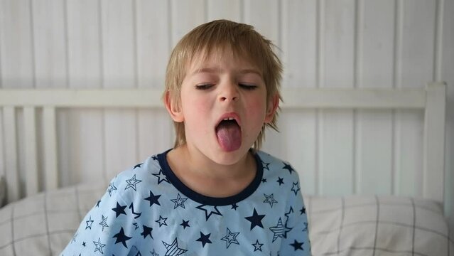Boy joking, sticking tongue out with silly expression. Child making face. Funny foolishness portrait of little baby boy on white background. Adorable Caucasian kid making crazy and comical gesture.