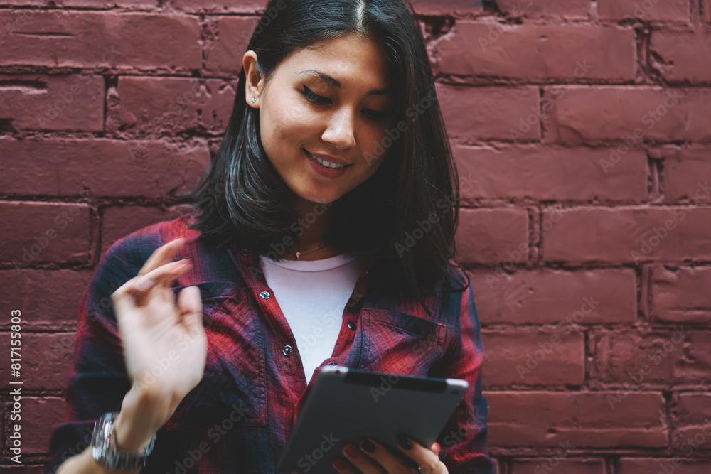 Poster happy young hipster girl holding modern digital tablet and messaging while enjoying time near copy s