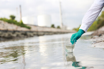 Ecologists in protective suits working near the oil refinery  and taking samples of water for...