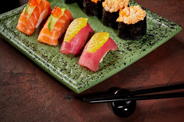 Hand-tossed nigiri with tuna and salmon and gunkan maki on green plate