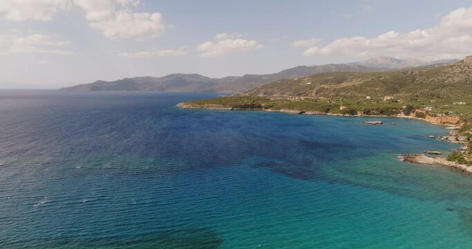 A breathtaking aerial perspective of Stoupa Kalogria Beach in Kardamili, Greece. The image captures the tranquil blue waters, sandy shore.