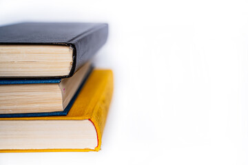 three books of different colors a yellow book, a blue book and a brown book lie on top of each...