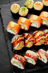 Sushi roll set with salmon, eel and cheese on slate board