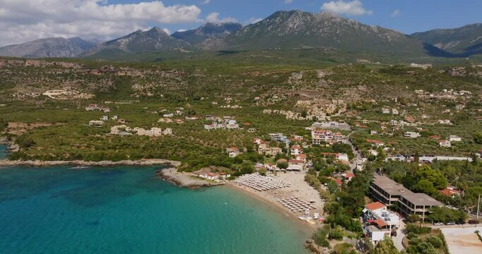 A breathtaking aerial perspective of Stoupa Kalogria Beach in Kardamili, Greece. The image captures the tranquil blue waters, sandy shore.