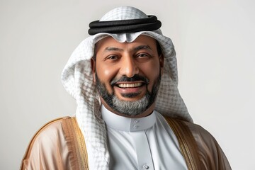 Portrait of a smiling Saudi man wearing a thobe and ghutra radiation on a white background, 