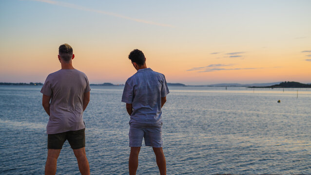 two friends looking at the sea horizon while pissing