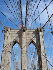 Brooklyn bridge with a flag on top of it. The bridge is very old and has a lot of wires