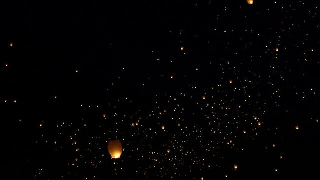 Panning across night sky filled with flying Chinese lanterns