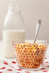 Delicious corn flakes with muesli in a bowl with a bottle of milk. A village background with a...