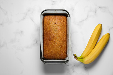 Banana bread loaf in a baking tin on marble background