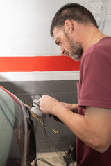 Mechanic Grinding Car Door at Auto Repair Workshop