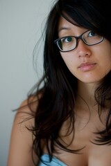 Fototapeta premium Young Asian Woman with Glasses Looking Thoughtfully at the Camera