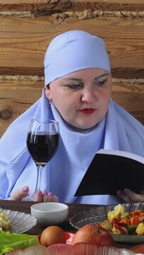 A Jewish woman in blue at the Pesach Seder table reads kiddush with a glass of wine. Vertical video