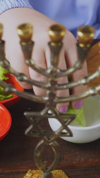 A Jewish woman in blue at the Pesach Seder table dips karpas in salt water. Vertical video