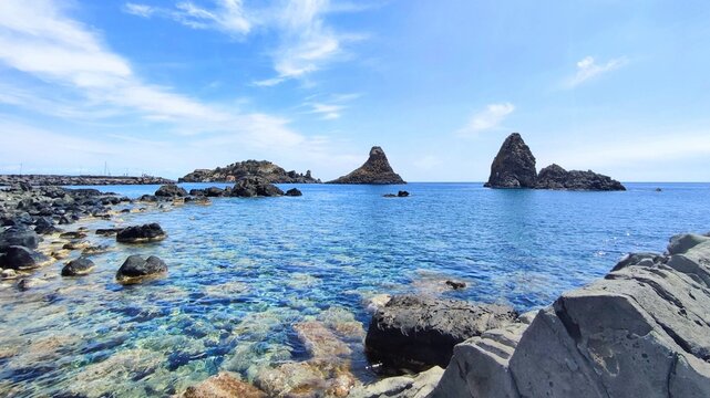 Photo of the Cyclopean isles in Aci Trezza, Italy. The Cyclopean isles are a row of basaltic columns piled one above another, they situated outside of the Aci Trezza town in Sicily, Italy.