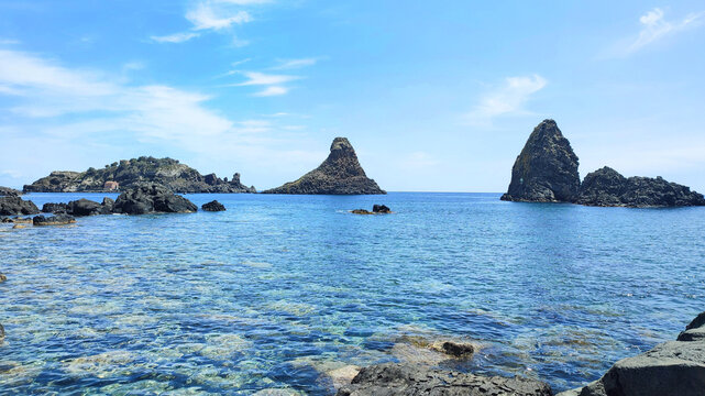 Photo of the Cyclopean isles in Aci Trezza, Italy. The Cyclopean isles are a row of basaltic columns piled one above another, they situated outside of the Aci Trezza town in Sicily, Italy.