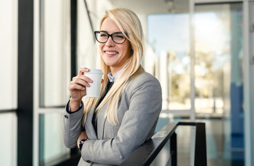 Beautiful Caucasian woman company CEO wearing glasses and drinking coffee on break outside her...