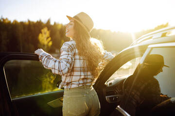 Young woman enjoying and having fun in their vacations outdoors leaning out car window. Road trip. 