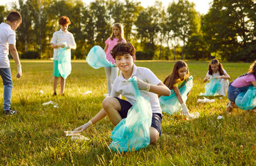 Save planet. Portrait of little boy who collects trash in garbage bag in forest or in park. Smiling...