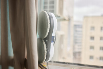 A robotic white Automotive tire is cleaning a glass window