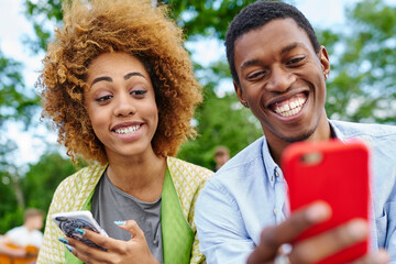 Positive african american friends with funny grimaces on face looking at front camera of modern smartphone and making selfie photos for blog spending together free time in urban setting