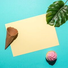 Tropical palm leaf with cupcake and ice cream cone on bright blue background. Minimal summer...