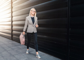 Stylish businesswoman walking outside wearing smart casual clothes.