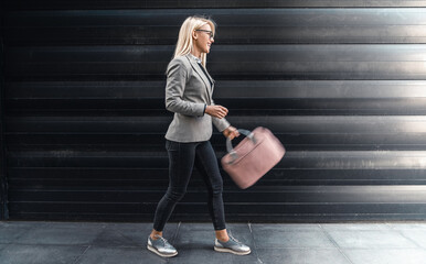 Female entrepreneur in motion on the way to work. Stylish businesswoman walking outside wearing...