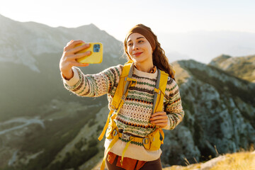 Young woman  taking selfie portrait on the top of mountain. Hiking, sport, travel and technology...