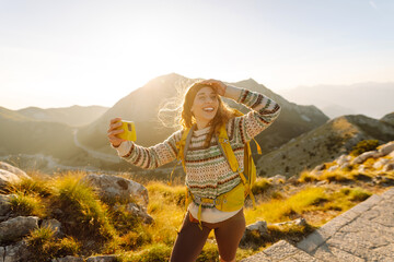 Young woman  taking selfie portrait on the top of mountain. Hiking, sport, travel and technology...